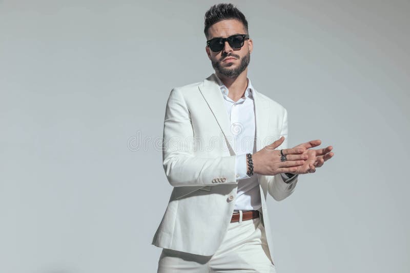 Guapo tipo sin afeitar con traje blanco frotando las palmas fotos de archivo