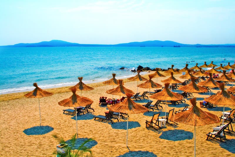 Guarda-chuvas da palha na praia calma em Bulgária