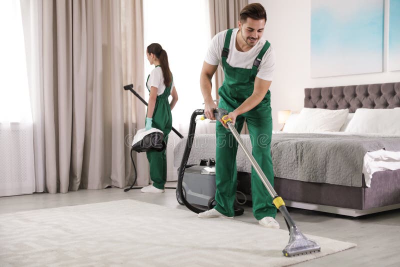 Guarda de serviço que limpam o quarto com o equipamento profissional fotografia de stock Guarda de serviço que limpam o quarto com o equipamento profissional fotografia de stock