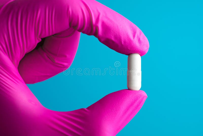 Guardando a luva do l?tex do rosa da m?o da enfermeira das drogas da c?psula do comprimido foto de stock Guardando a luva do l?tex do rosa da m?o da enfermeira das drogas da c?psula do comprimido foto de stock