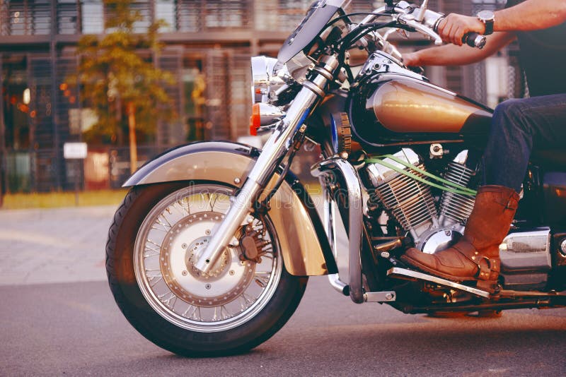 Guida del motociclista su un motociclo Vista dal basso delle gambe in stivali di cuoio Un uomo vicino al centro dell'ufficio su u immagini stock Guida del motociclista su un motociclo Vista dal basso delle gambe in stivali di cuoio Un uomo vicino al centro dell'ufficio su u immagini stock