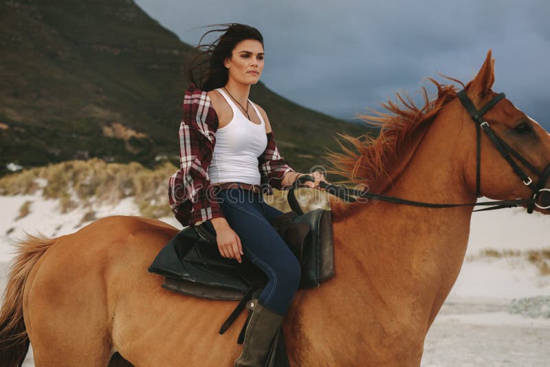 Guida della donna con il suo stallone sulla spiaggia fotografie stock libere da diritti Guida della donna con il suo stallone sulla spiaggia fotografie stock libere da diritti