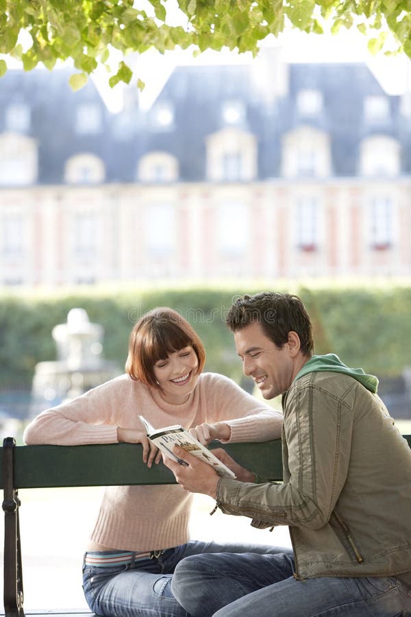 Guide de lecture de couples sur le banc de parc images stock Guide de lecture de couples sur le banc de parc images stock