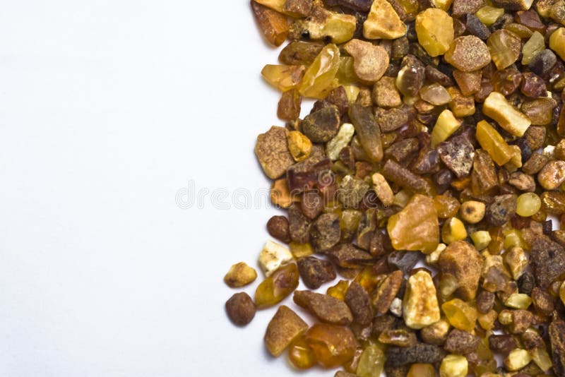 A closeup view of a pile of amber pebbles or small stones on a white background. A closeup view of a pile of amber pebbles or small stones on a white background.