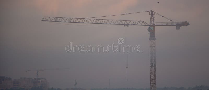 guindaste de construção muito alto na névoa da manhã, contra o fundo cinzento do céu fotografia de stock royalty free guindaste de construção muito alto na névoa da manhã, contra o fundo cinzento do céu fotografia de stock royalty free