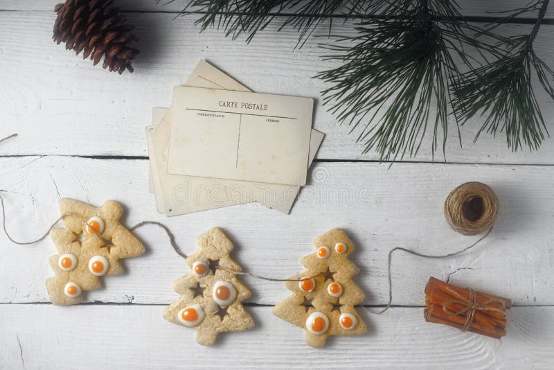 Guirnalda de las galletas y de la postal de la Navidad en la opinión superior del fondo de madera blanco fotos de archivo Guirnalda de las galletas y de la postal de la Navidad en la opinión superior del fondo de madera blanco fotos de archivo