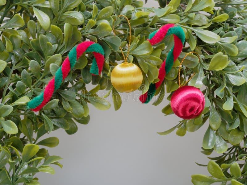 Guirnalda o guirnalda artificial de la Navidad hecha por la hoja plástica adornada por el bastón rojo y blanco y la manzana roja imagen de archivo libre de regalías Guirnalda o guirnalda artificial de la Navidad hecha por la hoja plástica adornada por el bastón rojo y blanco y la manzana roja imagen de archivo libre de regalías