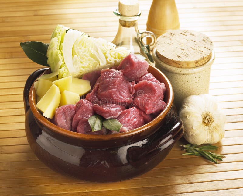 Raw cubes of beef with potatoes, cabbages, garlic, rosemary in a pot. Raw cubes of beef with potatoes, cabbages, garlic, rosemary in a pot