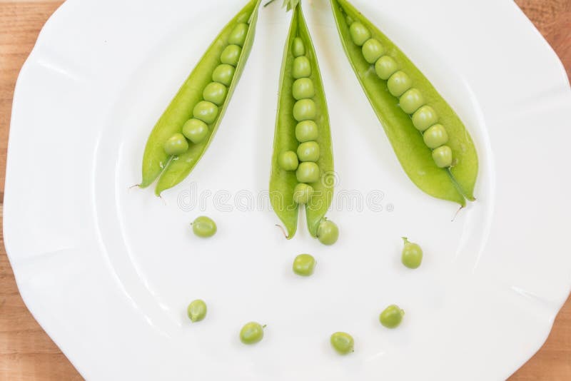 Guisantes verdes en una placa blanca imágenes de archivo libres de regalías Guisantes verdes en una placa blanca imágenes de archivo libres de regalías