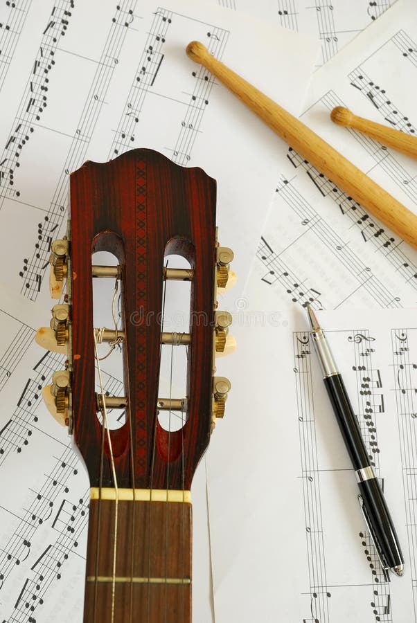 Guitar, drum sticks with pen on music score