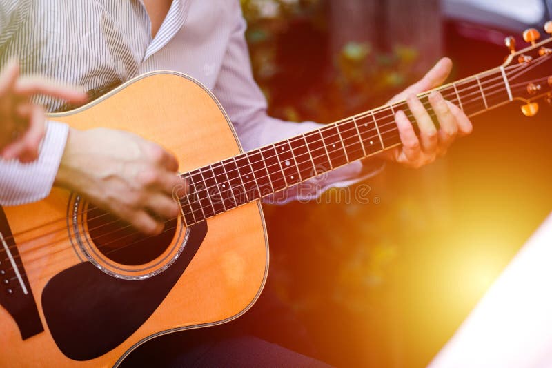 Guitar with a man`s male hands playing the guitar on wooden wall background, electric or acoustic guitar with nature light. Concep stock photo Guitar with a man`s male hands playing the guitar on wooden wall background, electric or acoustic guitar with nature light. Concep stock photo