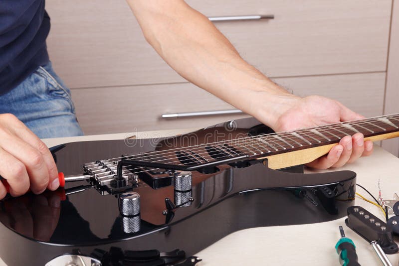 Guitar Master Tunes Tremolo Bridge on Modern Electric Guitar Stock