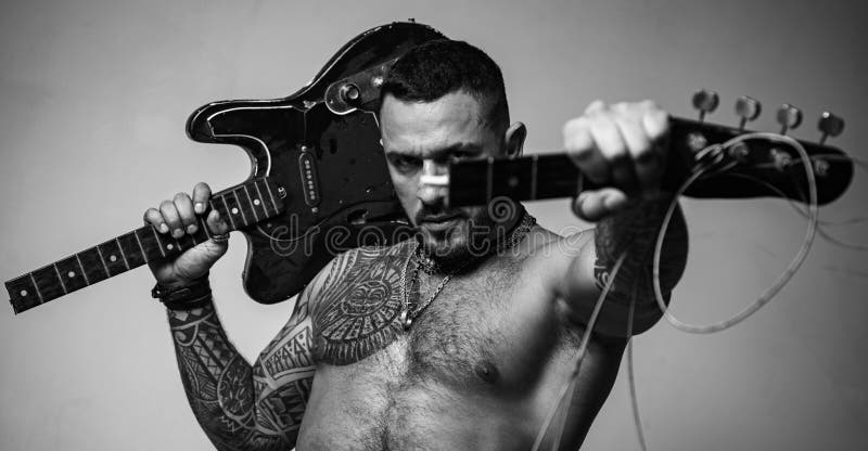 Guitar player at rock concert. sexy abs of tattoo man hold broken electro guitar. sport and fitness. brutal sportsman