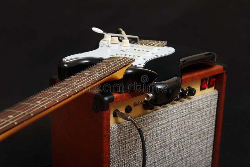Guitar Tube Amplifier with Black Electric Guitar on Black Background