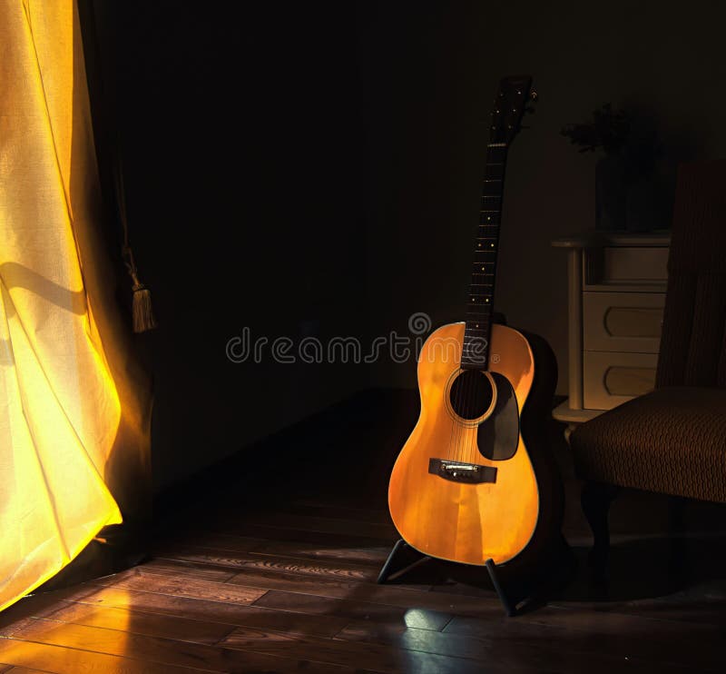 Acoustic Spanish guitar on a stand in the moody shadows of a dark room with bright light coming in from behind a yellow curtain. Acoustic Spanish guitar on a stand in the moody shadows of a dark room with bright light coming in from behind a yellow curtain