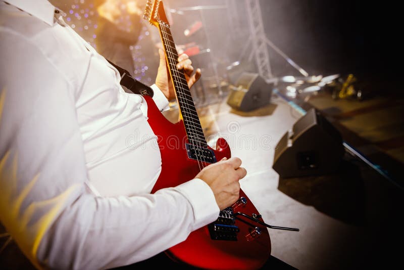 Guitarra del juego de la mano del guitarrista en etapa del concierto con la guitarra roja fotografía de archivo libre de regalías Guitarra del juego de la mano del guitarrista en etapa del concierto con la guitarra roja fotografía de archivo libre de regalías