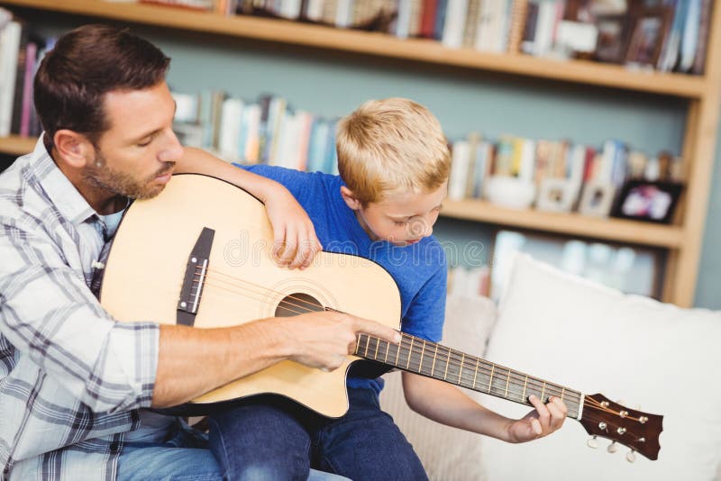 Guitarra do jogo de Teaching Son To do pai fotografia de stock royalty free Guitarra do jogo de Teaching Son To do pai fotografia de stock royalty free