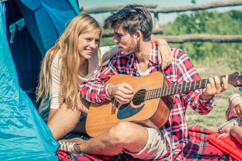 Guitarra do jogo dos pares em um acampamento imagem de stock Guitarra do jogo dos pares em um acampamento imagem de stock