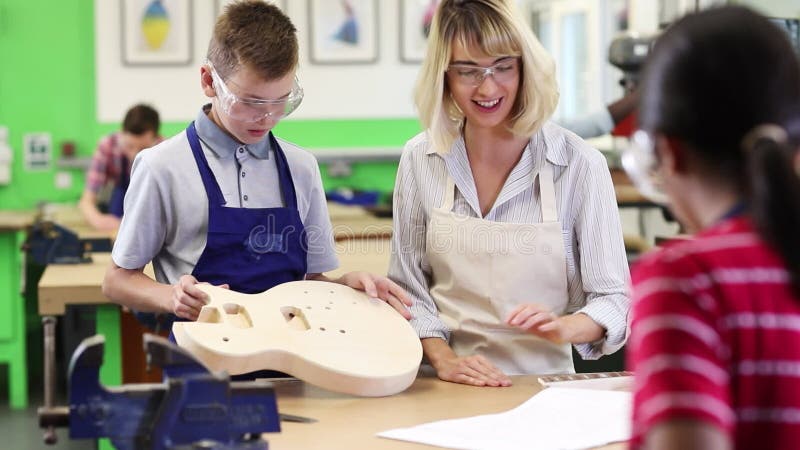 Guitarra masculina de ajuda da construção do estudante da High School do professor na lição da carpintaria