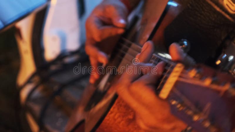 Guitarrista de rua toca violão à noite à luz da fogueira. movimento lento