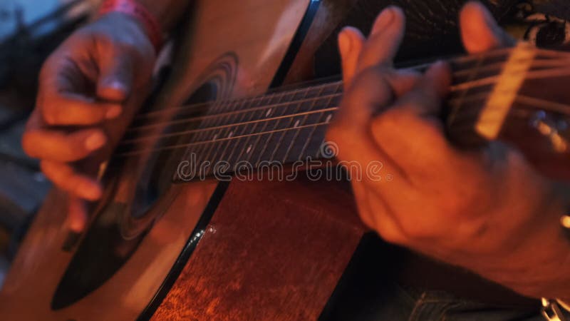 Guitarrista de rua toca violão à noite à luz da fogueira. movimento lento