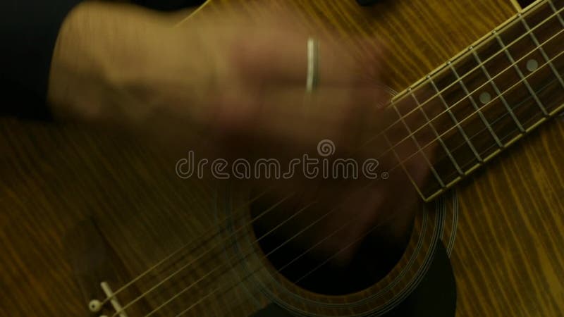 Guitarrista masculino que joga a guitarra acústica, close up