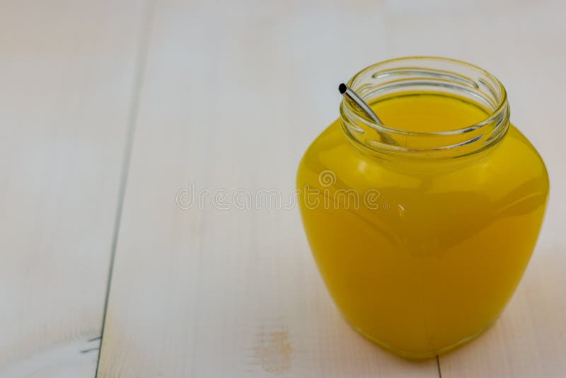 Gul fruktsaft i exponeringsglascloseup på det vita träbrädet Ny exotisk fruktdrink arkivbild Gul fruktsaft i exponeringsglascloseup på det vita träbrädet Ny exotisk fruktdrink arkivbild