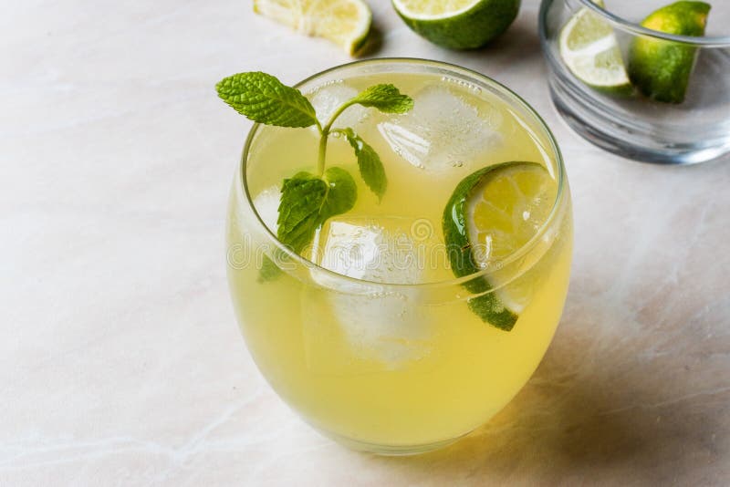 Gul lemonadcoctail med limefrukt och is arkivbilder