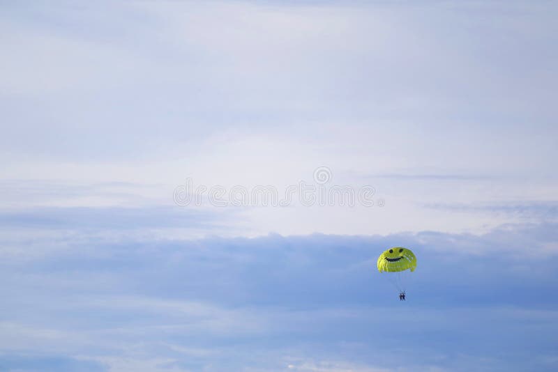 Gul lycklig yta Parachute som flyger i Light Blue Sky arkivbild Gul lycklig yta Parachute som flyger i Light Blue Sky arkivbild