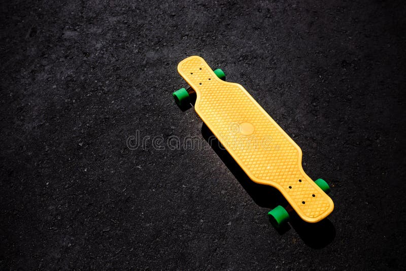 Gul plast- longboard på asfaltyttersidan royaltyfria foton Gul plast- longboard på asfaltyttersidan royaltyfria foton