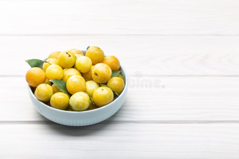 Gul plommonmirabellefrukt i bunke på den vita trätabellen kopiera avst?nd fotografering för bildbyråer Gul plommonmirabellefrukt i bunke på den vita trätabellen kopiera avst?nd fotografering för bildbyråer