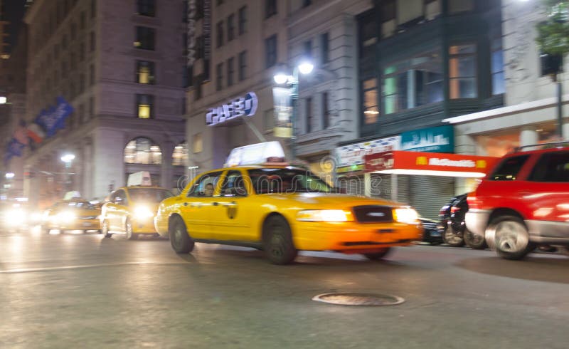 Gul taxi på natten i New York City i rörelsesuddighet royaltyfri bild Gul taxi på natten i New York City i rörelsesuddighet royaltyfri bild