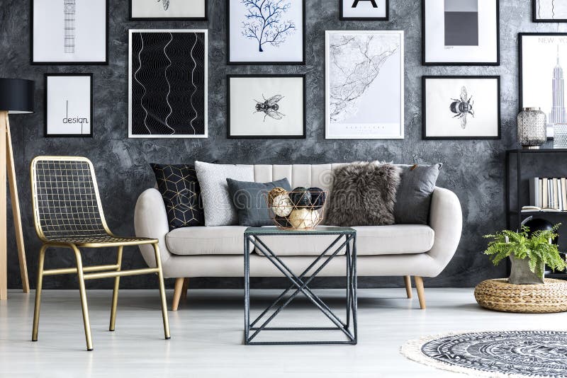 Guld- stol nära beige soffa i modern lägenhetinre med G royaltyfria foton