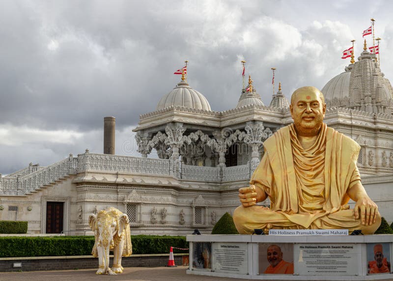 London, UK - Feb 23, 2024 - The gold colored statue of spiritual leader holiness pramukh swami maharaj front of Neasden temple (BAPS Shri Swaminarayan Mandir) against a nice cloudy sky background. Hindu temple in Neasden to build is constructed from Italian Marble, hand carved in India, Copy space, Selective focus. London, UK - Feb 23, 2024 - The gold colored statue of spiritual leader holiness pramukh swami maharaj front of Neasden temple (BAPS Shri Swaminarayan Mandir) against a nice cloudy sky background. Hindu temple in Neasden to build is constructed from Italian Marble, hand carved in India, Copy space, Selective focus