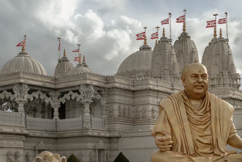 London, UK - Feb 23, 2024 - The gold colored statue of spiritual leader holiness pramukh swami maharaj front of Neasden temple (BAPS Shri Swaminarayan Mandir) against a nice cloudy sky background. Hindu temple in Neasden to build is constructed from Italian Marble, hand carved in India, Space for text, Selective focus. London, UK - Feb 23, 2024 - The gold colored statue of spiritual leader holiness pramukh swami maharaj front of Neasden temple (BAPS Shri Swaminarayan Mandir) against a nice cloudy sky background. Hindu temple in Neasden to build is constructed from Italian Marble, hand carved in India, Space for text, Selective focus