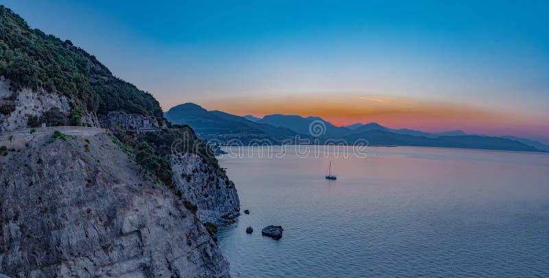 Gulf of Salerno, panorama seen at dawn. Calm sea, sailing boat at the bottom. Clear line of the coast. The first lights of the day. Gulf of Salerno, panorama seen at dawn. Calm sea, sailing boat at the bottom. Clear line of the coast. The first lights of the day.