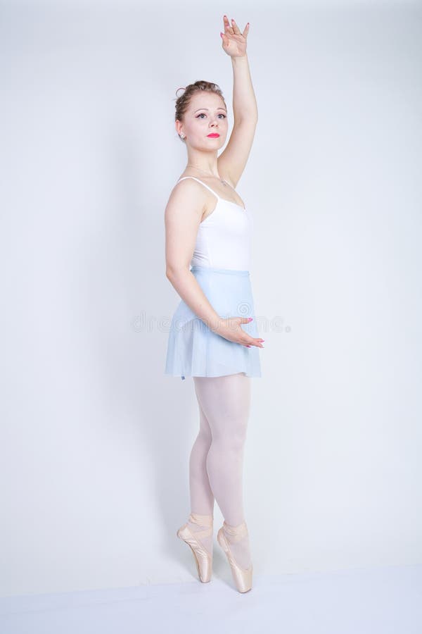 Gullig caucasian flicka i balettkläder som lär att vara en ballerina på en vit bakgrund i studion plus drömmar för ung kvinna för fotografering för bildbyråer Gullig caucasian flicka i balettkläder som lär att vara en ballerina på en vit bakgrund i studion plus drömmar för ung kvinna för fotografering för bildbyråer