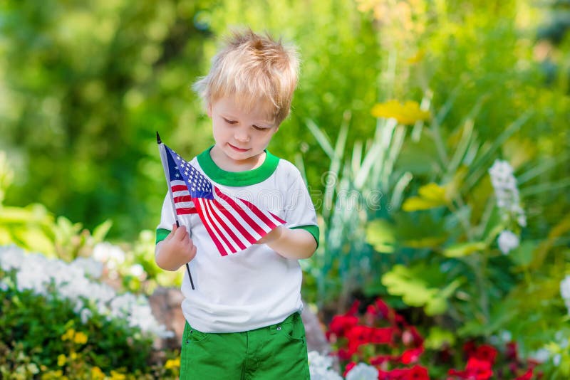 Gullig eftertänksam pys med den hållande amerikanska flaggan för blont hår royaltyfria foton Gullig eftertänksam pys med den hållande amerikanska flaggan för blont hår royaltyfria foton