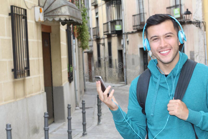 Gullig etnisk ung man som anv?nder hans smartphone f?r att lyssna till takten utomhus med kopieringsutrymme arkivfoton Gullig etnisk ung man som anv?nder hans smartphone f?r att lyssna till takten utomhus med kopieringsutrymme arkivfoton