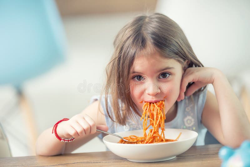 Cute little kid girl eating spaghetti bolognese at home. Cute little kid girl eating spaghetti bolognese at home.