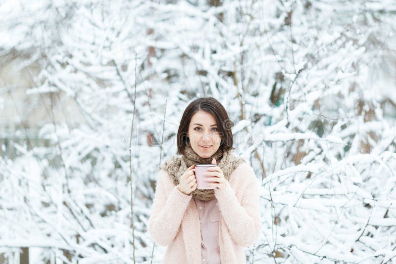 Gullig flicka med en rosa kopp kaffe i vinterskogen royaltyfria foton