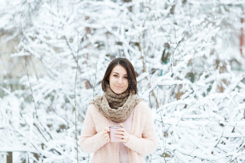 Gullig flicka med en rosa kopp kaffe i vinterskogen royaltyfria bilder