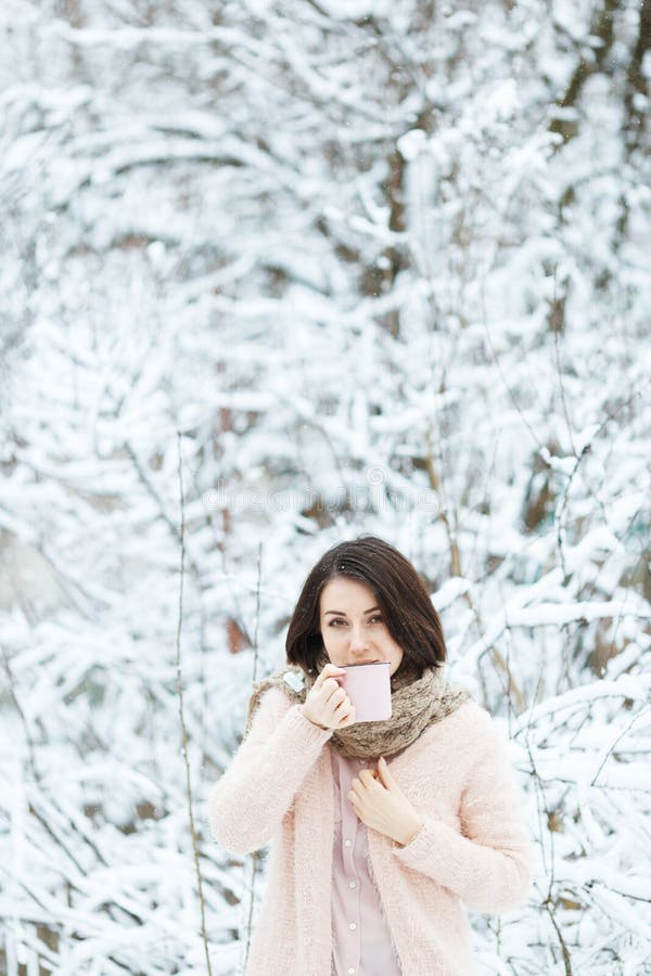 Gullig flicka med en rosa kopp kaffe i vinterskogen royaltyfria foton