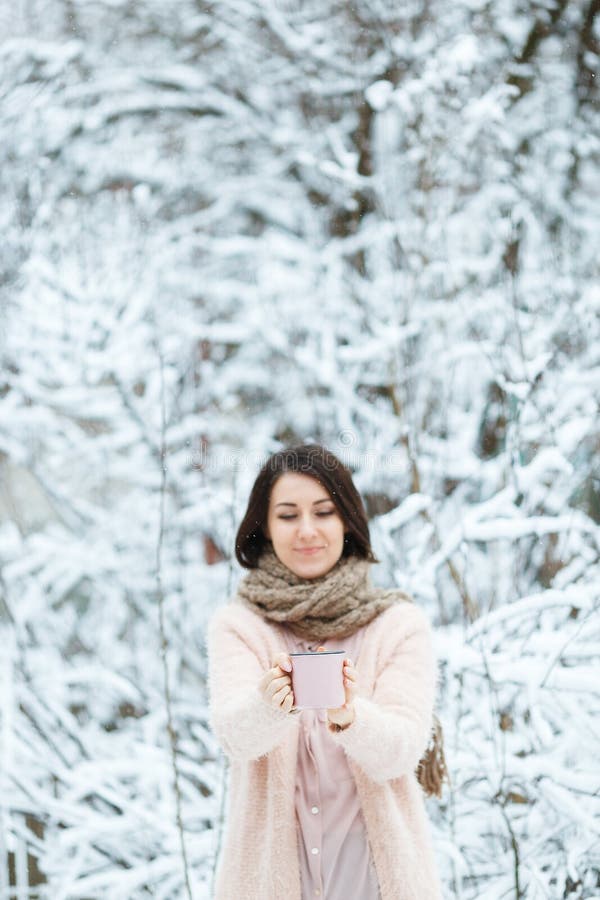 Gullig flicka med en rosa kopp kaffe i vinterskogen royaltyfria bilder