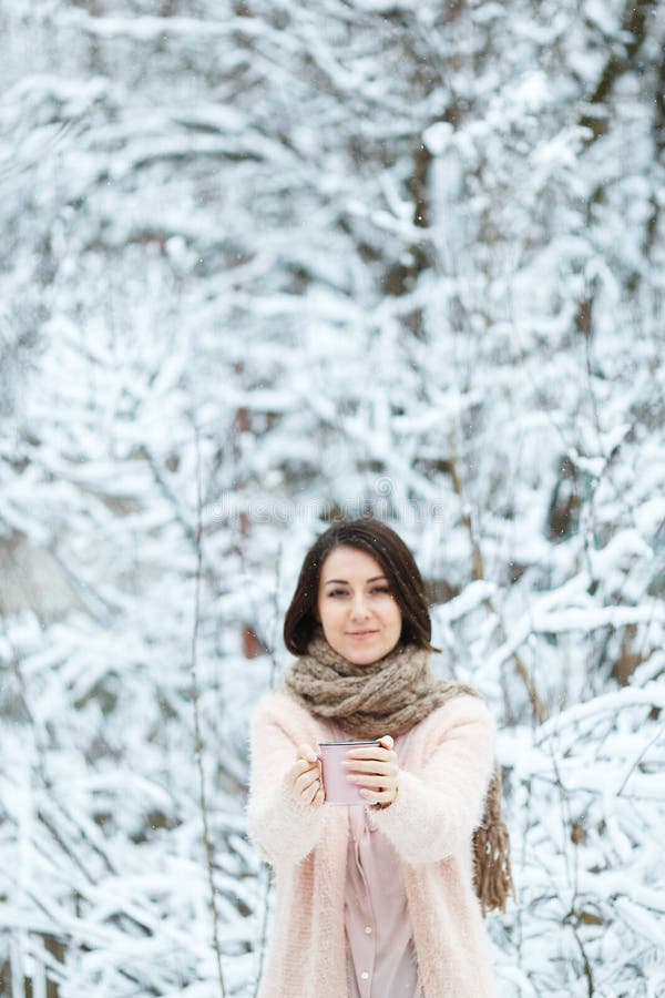 Gullig flicka med en rosa kopp kaffe i vinterskogen royaltyfri bild