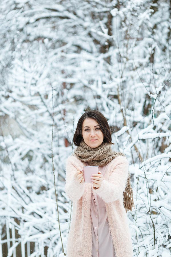 Gullig flicka med en rosa kopp kaffe i vinterskogen royaltyfria bilder