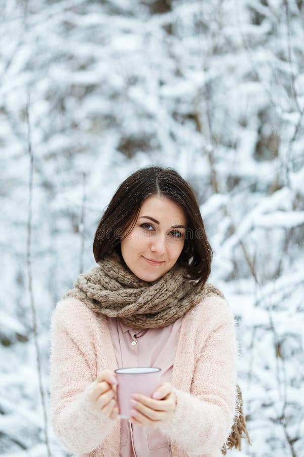 Gullig flicka med en rosa kopp kaffe i vinterskogen royaltyfri bild