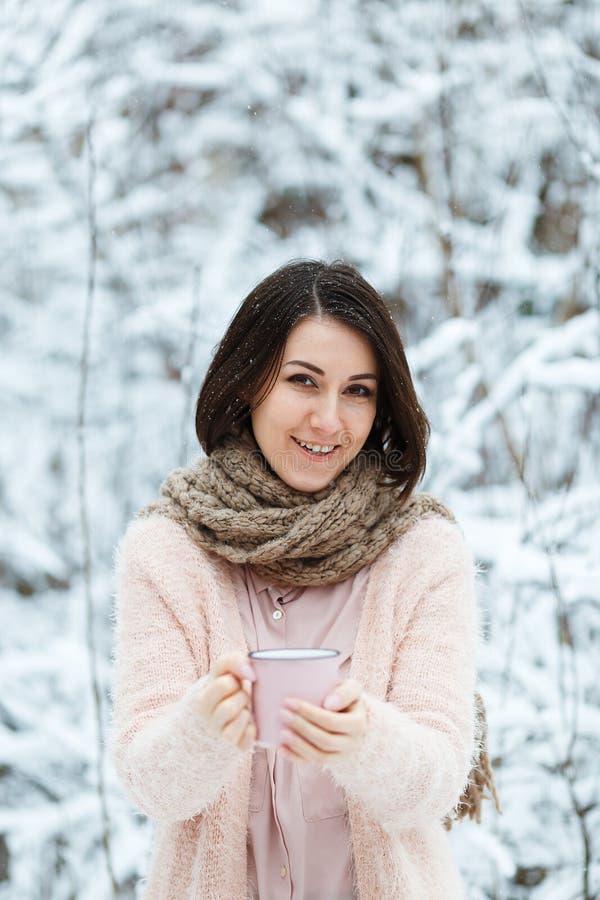 Gullig flicka med en rosa kopp kaffe i vinterskogen royaltyfria bilder