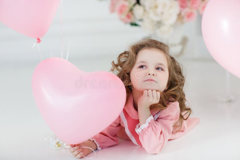 Gullig flicka på det vita golvet i studio med en grupp av rosa ballonger