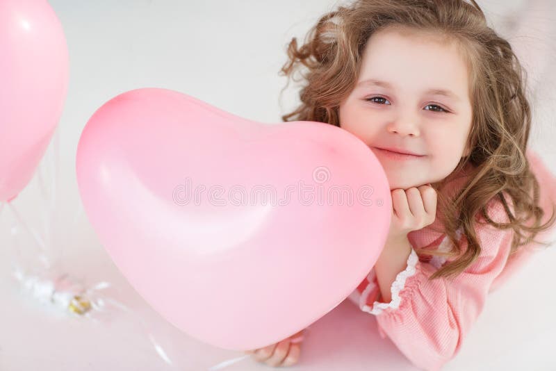 Gullig flicka på det vita golvet i studio med en grupp av rosa ballonger
